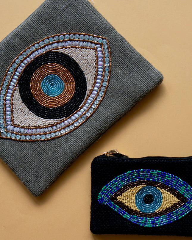 Two pouches with eye designs on a beige background
