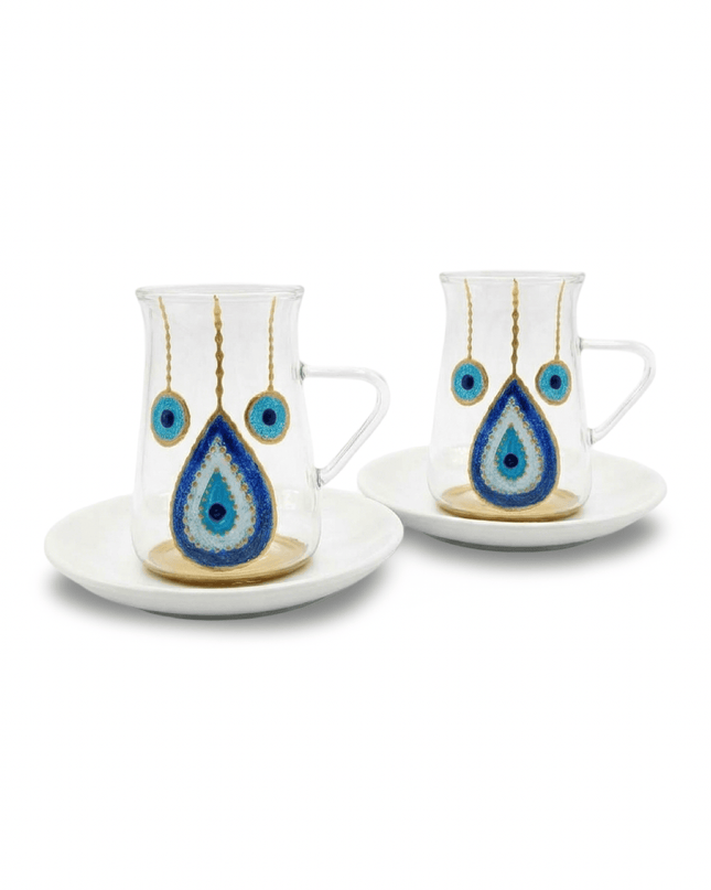 Clear glass tea cup with clear handle and hand-painted blue and gold evil eye on a round white porcelain saucer