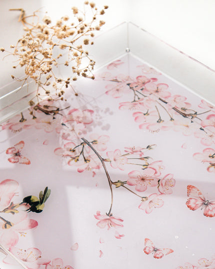 Floral patterned tray on a white surface with dried flowers.