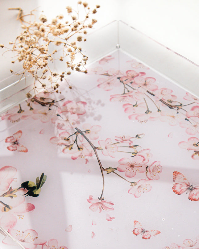 Floral patterned tray on a white surface with dried flowers.