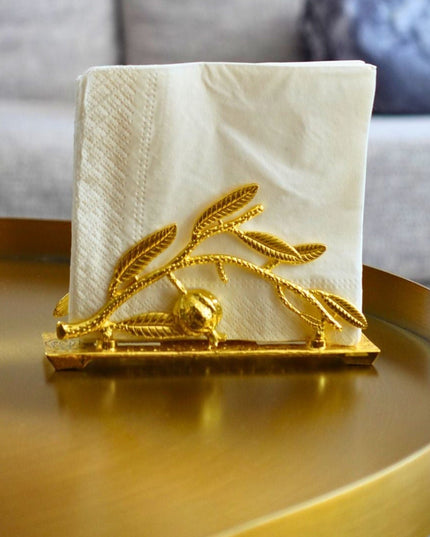 Decorative napkin holder with gold design on a round golden table.