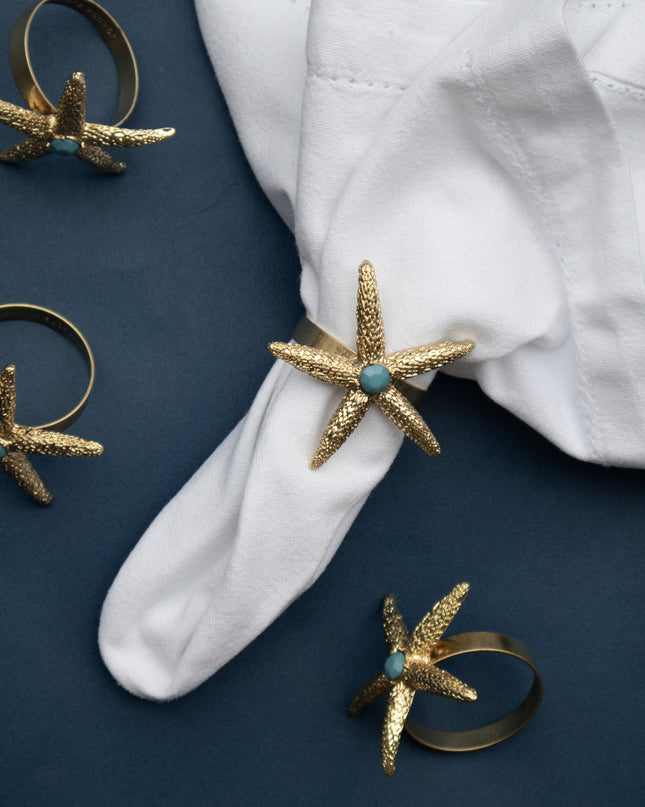 Starfish napkin rings on a white napkin with blue background