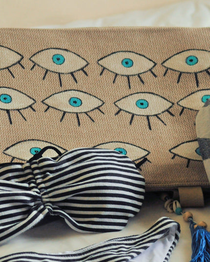 Striped bikini set with hand-painted evil eye beach bag on a light background