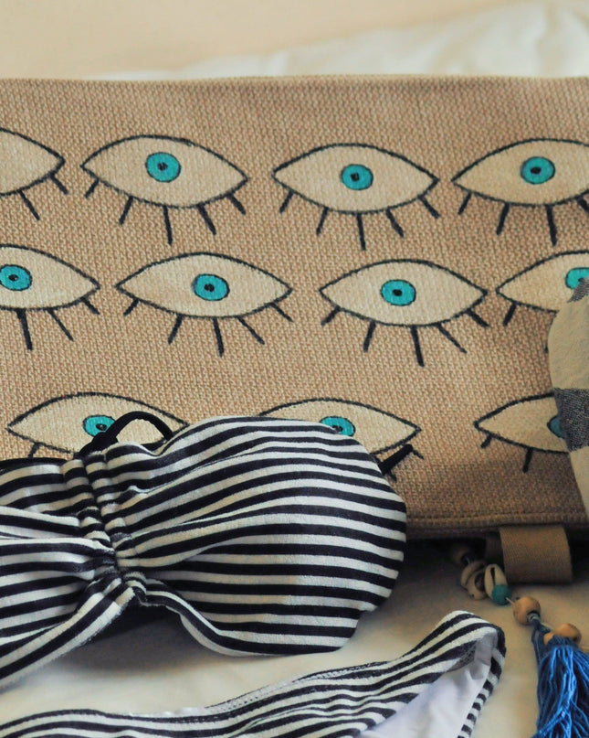 Striped bikini set with hand-painted evil eye beach bag on a light background