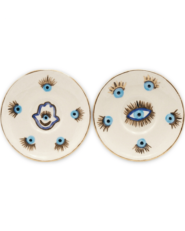 Sahar white ceramic dessert plates with gold rims, one with a blue and gold evil eye and one with a hamsa hand