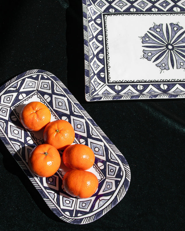 Decorative blue and white serving plates with mandarins on a black surface