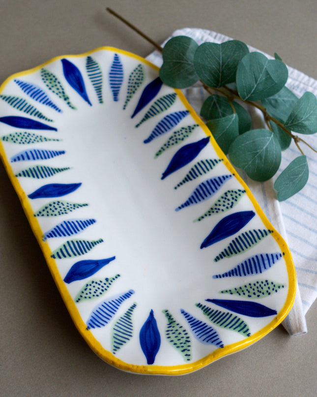 Decorative ceramic dish with blue leaf pattern on a gray surface