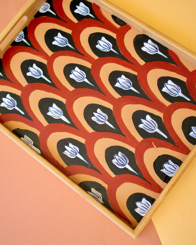 Decorative wooden tray with a pattern of black and white tulip designs on a peach background