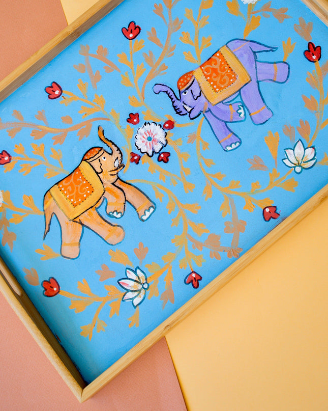 Decorative turquoise wooden tray with hand-painted elephants and flowers on a colorful background