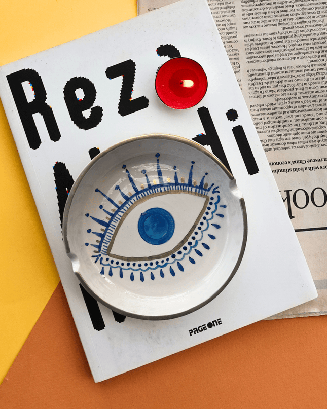Decorative hand-painted evil eye ashtray on a magazine