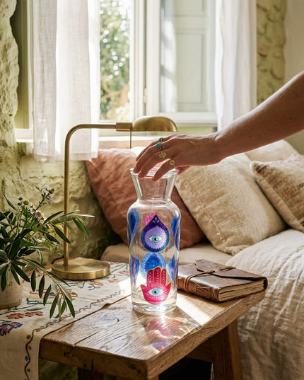 Lifestyle scene of the Jewel Evil Eye & Hamsa Water Carafe on a table