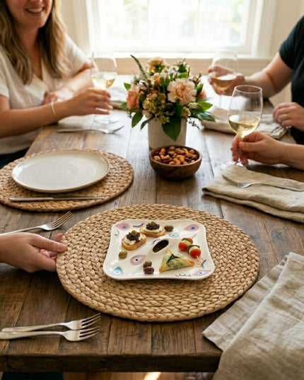 Rangeela hand-painted evil eye appetizer plate with a center hole handle, styled with crostini, caprese skewers and olives on a wooden table