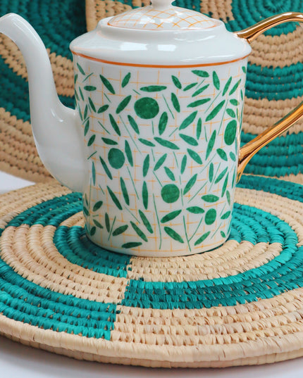 Teapot with green leaf pattern on green woven grass placemats