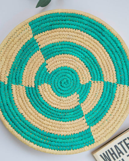Round woven mat with green and beige spiral pattern on a light background