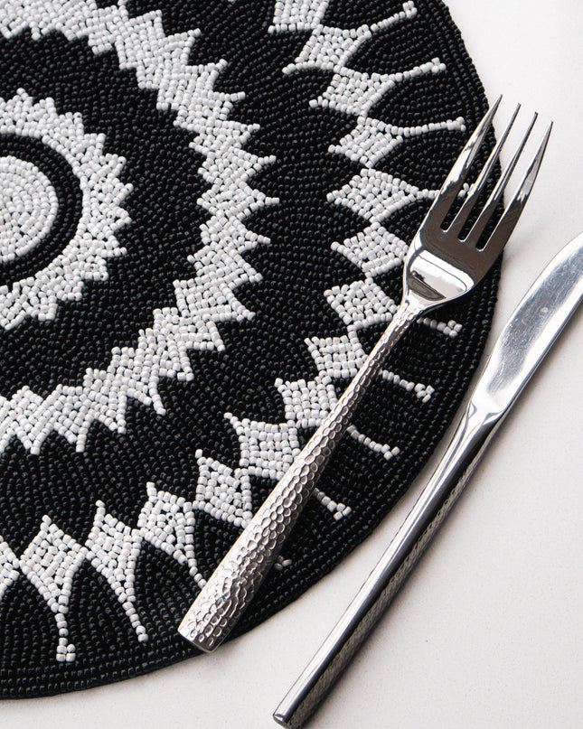 Black and white patterned placemat with a fork and knife on a white surface