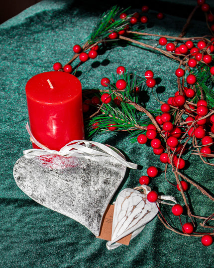 Red candle, heart-shaped ornaments and decorative branches on a green surface