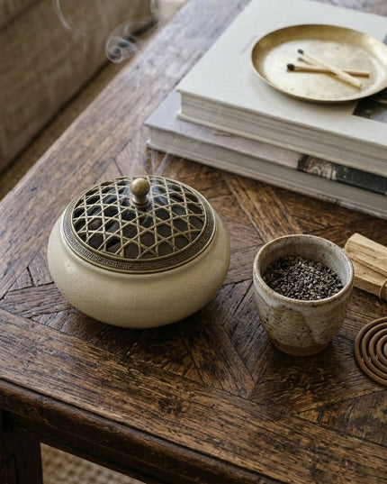 Chakra incense holder in use on a wooden table with books and a cup of tea