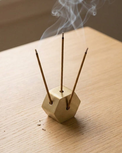 Shatkon incense holder standing upright on a wooden table with three incense sticks burning