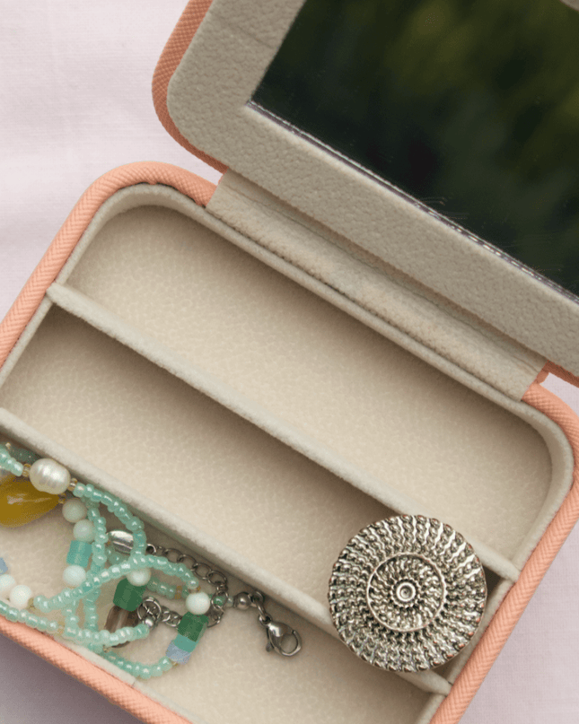 Open jewelry box with a bracelet and pendant on a light background