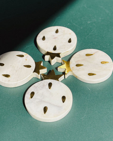 white marble pomegranate shaped coasters on a green surface