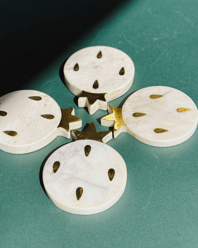 white marble pomegranate shaped coasters on a green surface