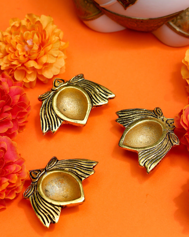 Decorative gold diyas on an orange background with flowers