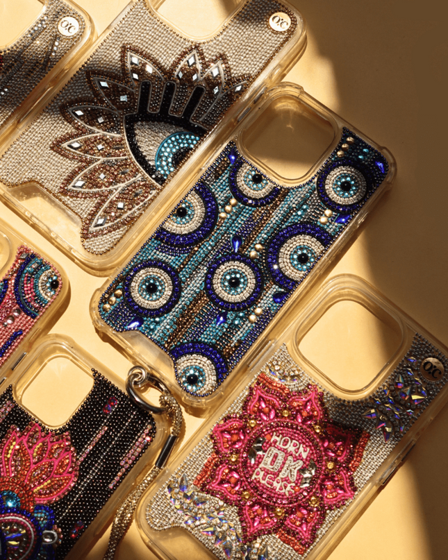 Decorative hand-beaded iphone cases with intricate designs and rhinestones on a beige background