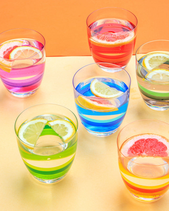 Set of colorful glasses with striped design and fruit slices on a gradient background