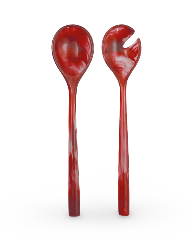 Two red resin salad servers on a white background
