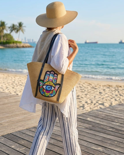 Casa Duniya Sequin Evil Eye and Hamsa Straw Bag Beige Carried on a Boardwalk by the Beach Adina Evil Eye Beach Bag
