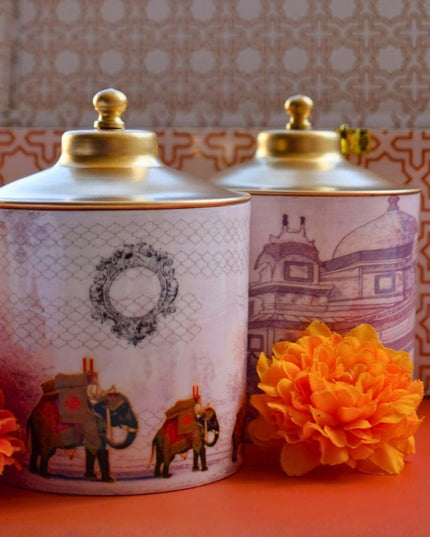 Two decorative jars with gold lids on a red surface, with a patterned box in the background.