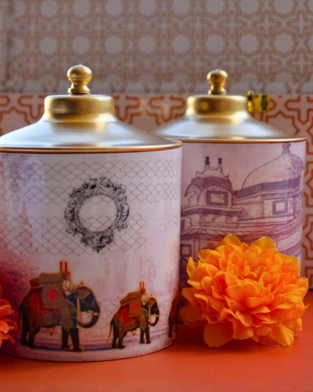 Two decorative jars with gold lids on a red surface, with a patterned box in the background.
