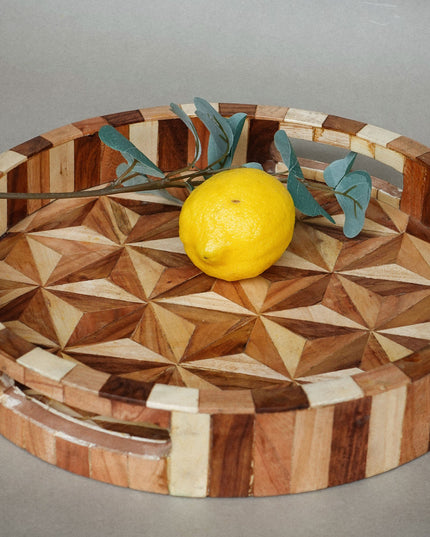 Wooden tray with geometric pattern and lemon on a gray background